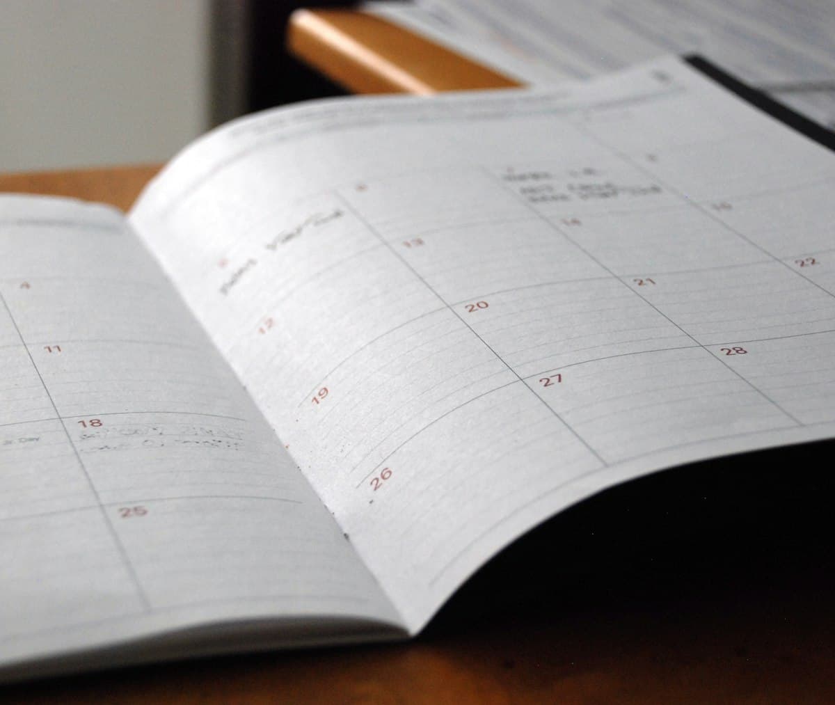 Open monthly planner on a wooden desk for scheduling business days