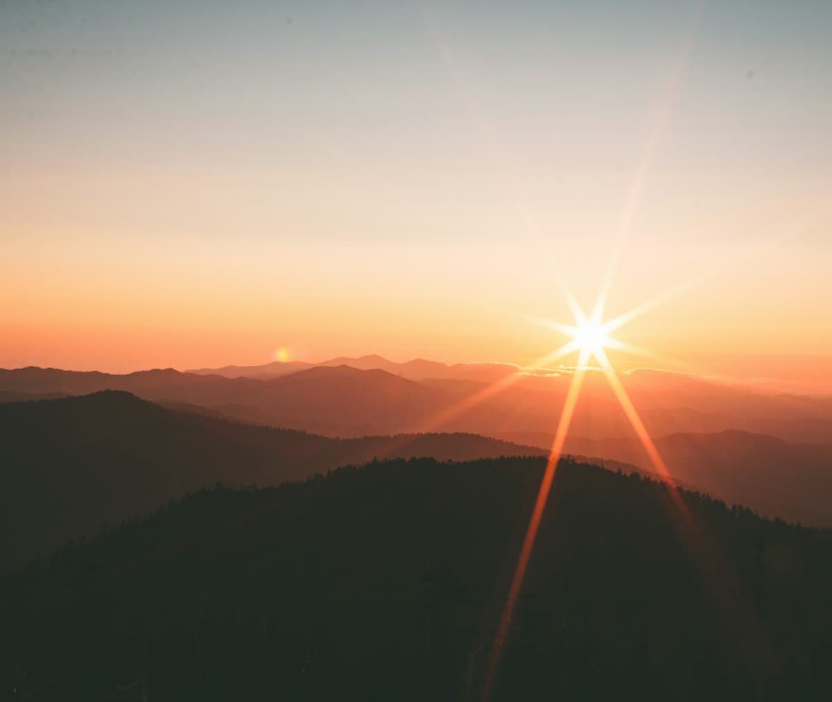 Silhouette of mountains against a glowing orange sky at sunset, when the sun sets