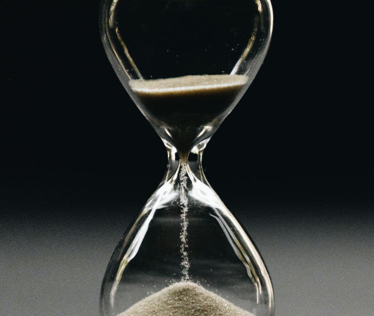 Clear glass hourglass with sand running, a symbol of time duration