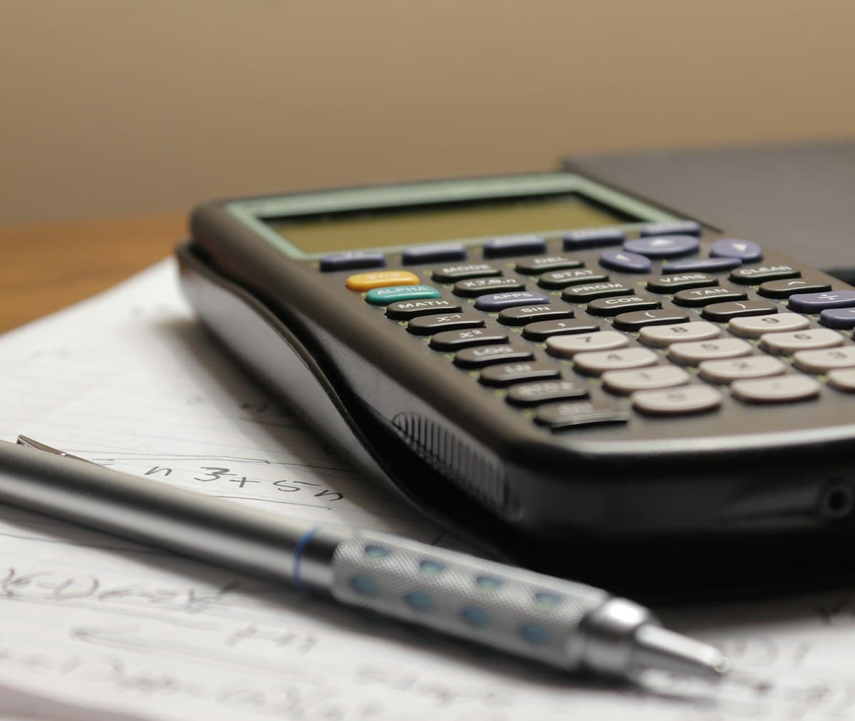 Calculator and a pen on a piece of paper for working out take-home pay