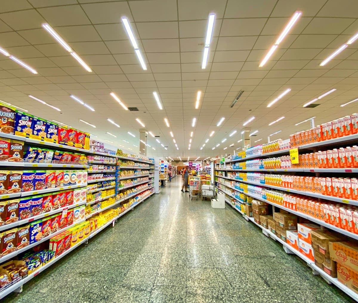 Grocery store aisle with shelves stocked with cereal boxes and milk cartons