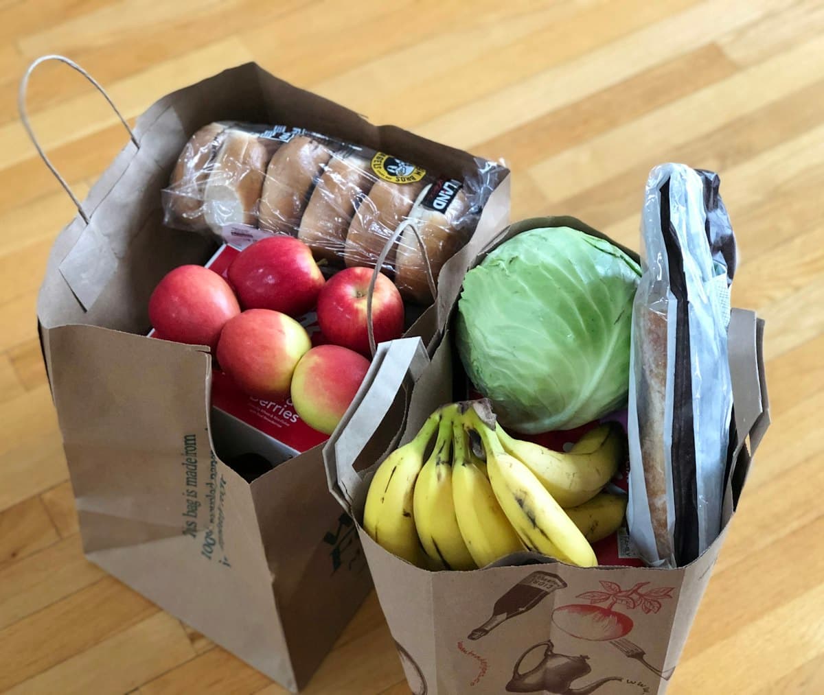 Apples and bananas in a brown cardboard box sold by weight at the grocery store