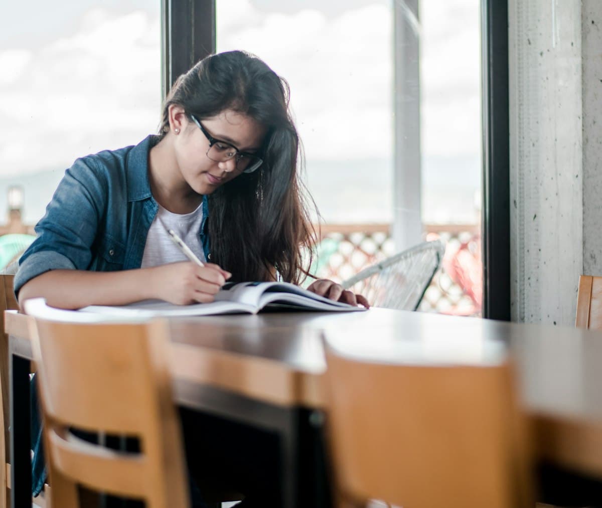 Student writing in a book while studying for exams and coursework