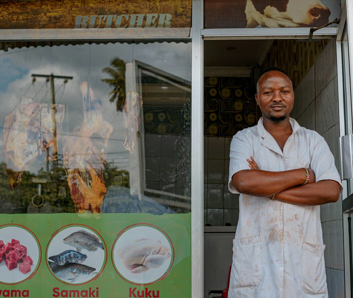 Shop owner standing outside a store with arms crossed, hoping the business breaks even