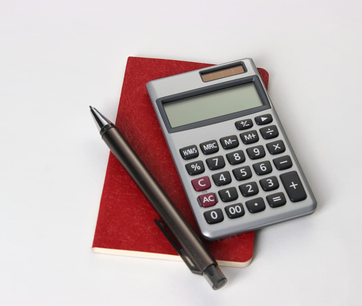 Black and silver calculator beside a pen for adding up business costs