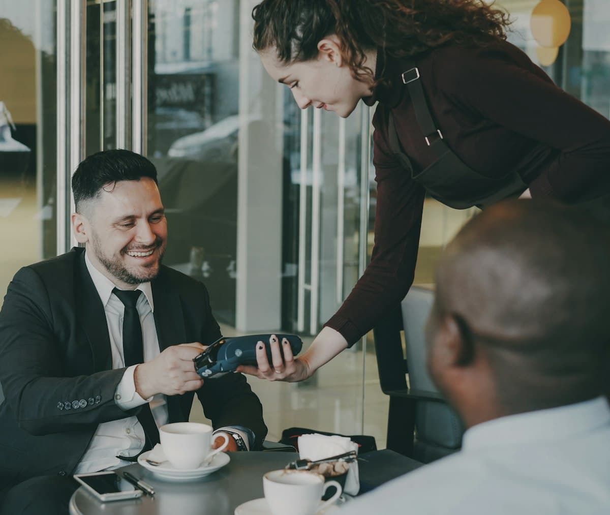 Man paying the restaurant bill with a credit card at a cafe table