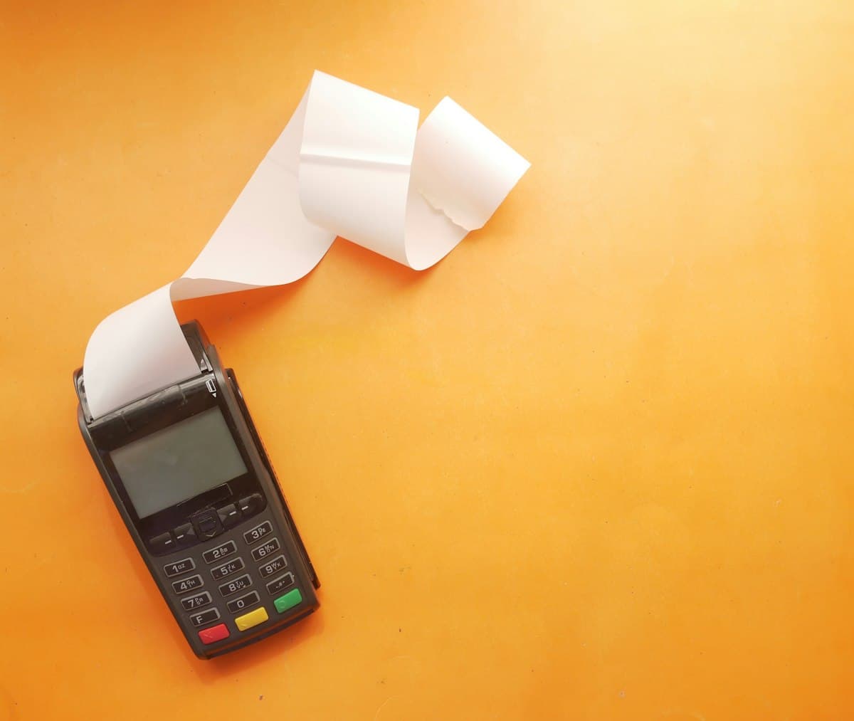 Payment terminal with a long paper receipt on an orange background